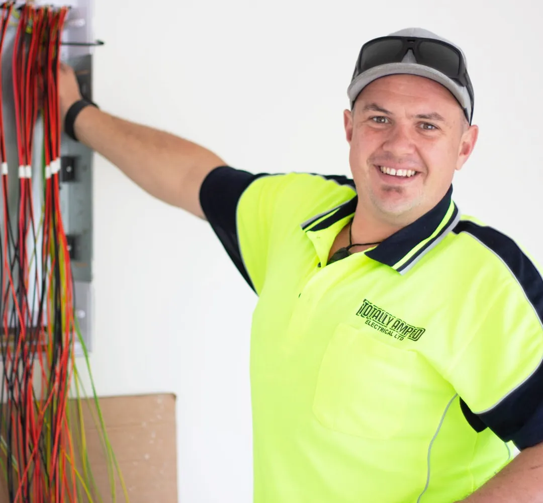 Coel Jackson, owner of Totally Amped Electrical, smiling at a switchboard prewire
